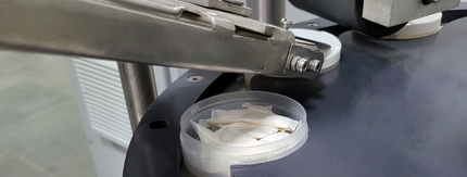 open can of nicotine pouches with compressor lid on top in a factory setting